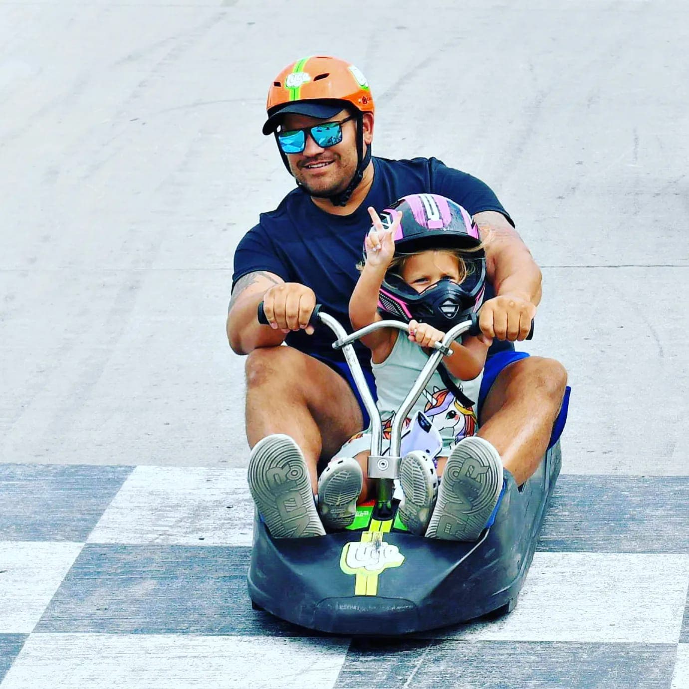 Tyler and Emma riding a luge down the track together